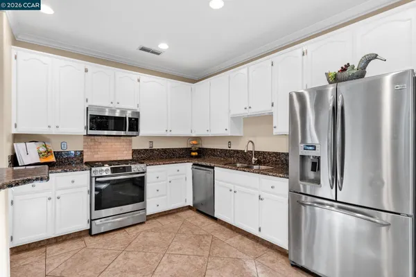 a kitchen with granite countertop white cabinets and stainless steel appliances