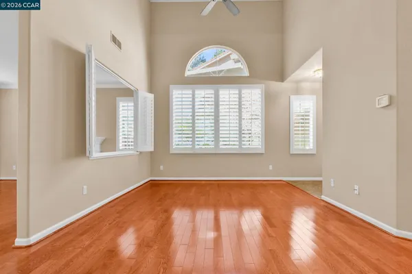 a view of an empty room with wooden floor and a window