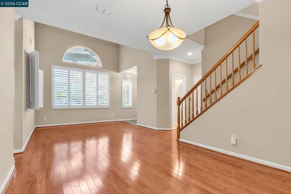 a view of an empty room with stairs and wooden floor