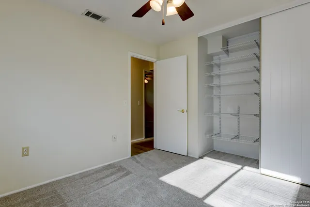 an empty room with closet and a ceiling fan