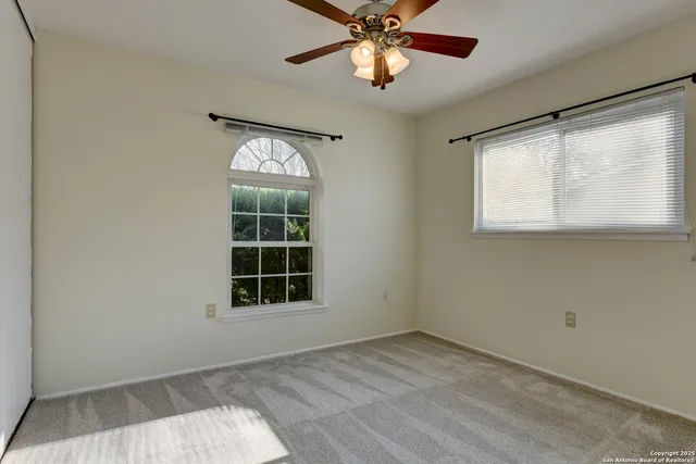 an empty room with a window and ceiling fan