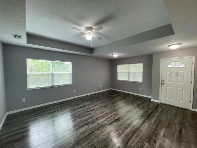 a view of an empty room with window and wooden floor