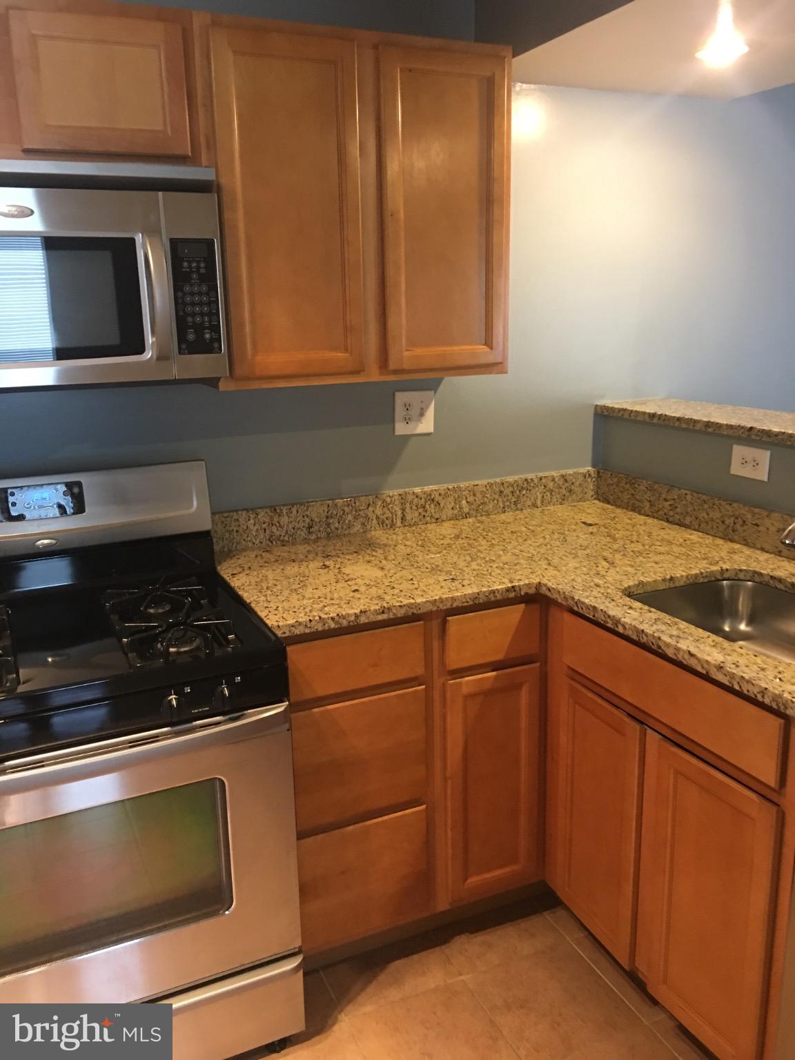 a kitchen with granite countertop stainless steel appliances a stove microwave and sink