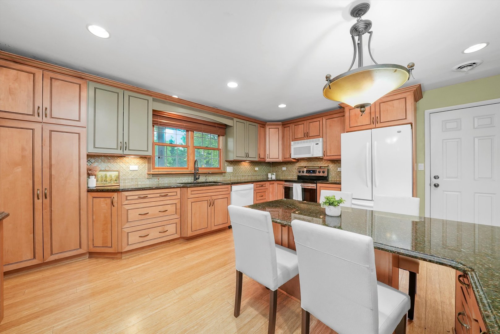 1406 Lincoln Road McHenry, IL 60051 - Photo 14 of 39 a kitchen with granite countertop a stove a sink dishwasher a dining table and chairs with wooden floor