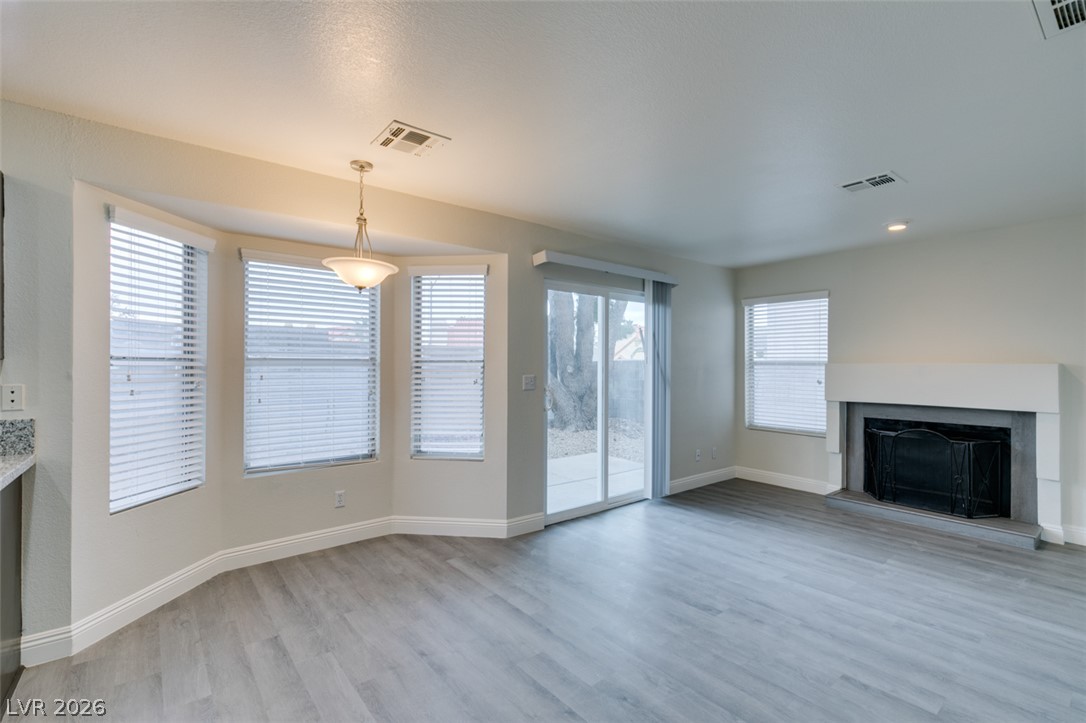 1738 Toltec Circle Henderson, NV 89014 - Photo 28 of 46 A well-lit living area features gray hardwood flooring, a fireplace, and a sliding door leading to an outdoor patio.