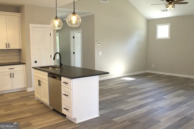 a kitchen with granite countertop a sink cabinets and wooden floor