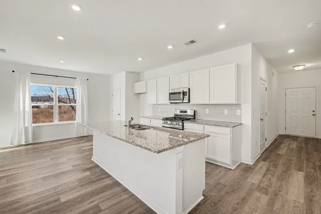 a large kitchen with kitchen island a sink wooden floor and white cabinets