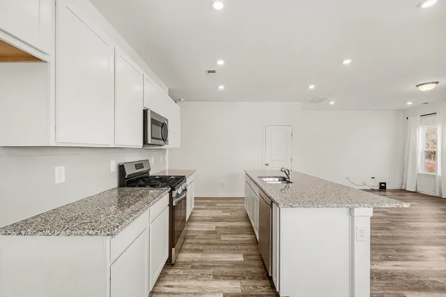 a kitchen with stainless steel appliances granite countertop a sink stove and cabinets