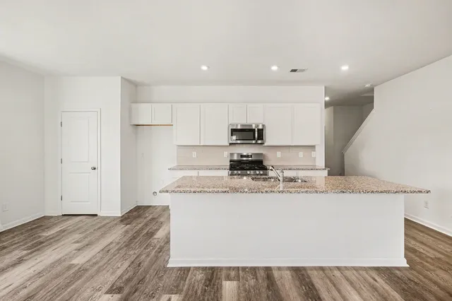 a large kitchen with stainless steel appliances granite countertop a stove a sink and a refrigerator