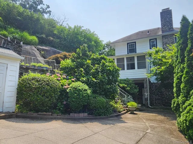 a view of a house with potted plants and a bench in front of it