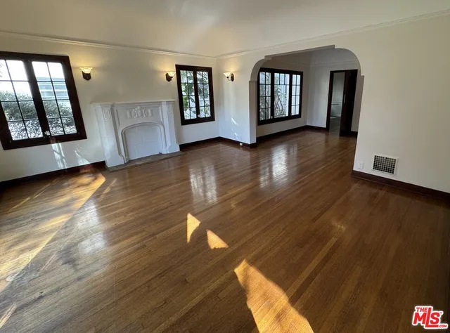 a view of an empty room with window and wooden floor