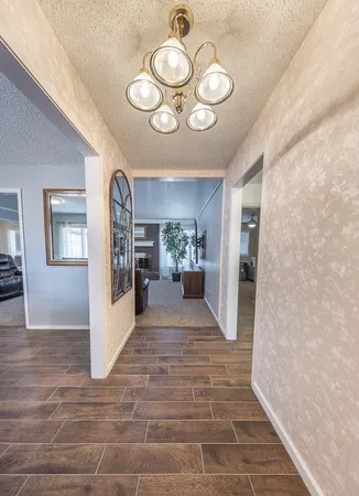 a view of a hallway with wooden floor and a chandelier