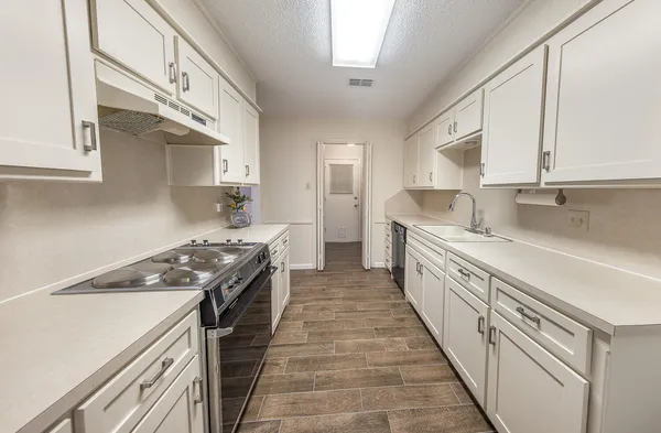 a kitchen with granite countertop a sink a stove oven and white cabinets