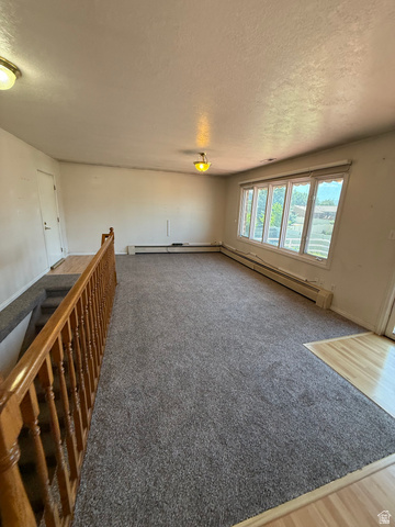 328 Heather Ridge Circle Sandy, UT 84070 - Photo 12 of 32 Carpeted living area featuring a prominent wood railing, large bay window, and baseboard heating