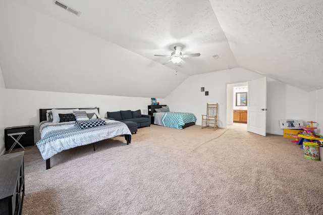a spacious bedroom with a bed a couch and a chandelier