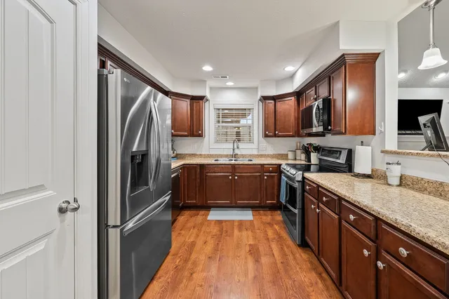 a large kitchen with stainless steel appliances granite countertop a refrigerator and a sink