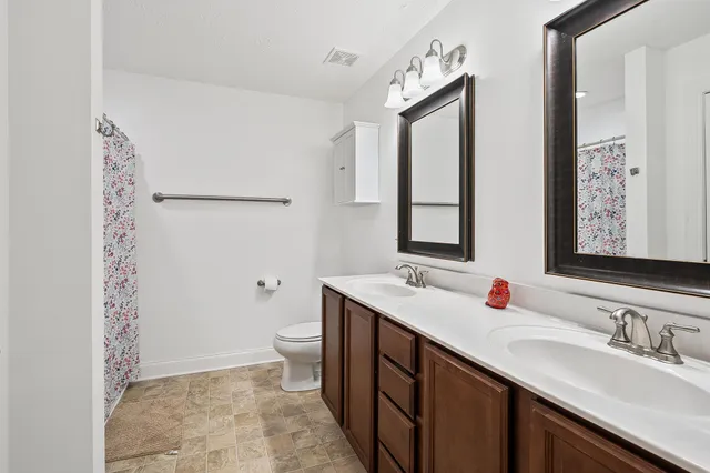 a bathroom with a double vanity sink toilet and mirror