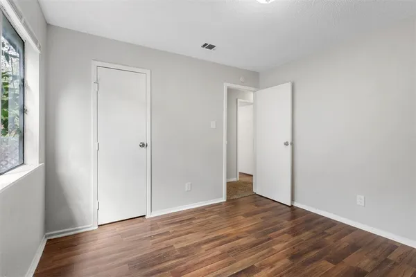 an empty room with wooden floor and a ceiling fan