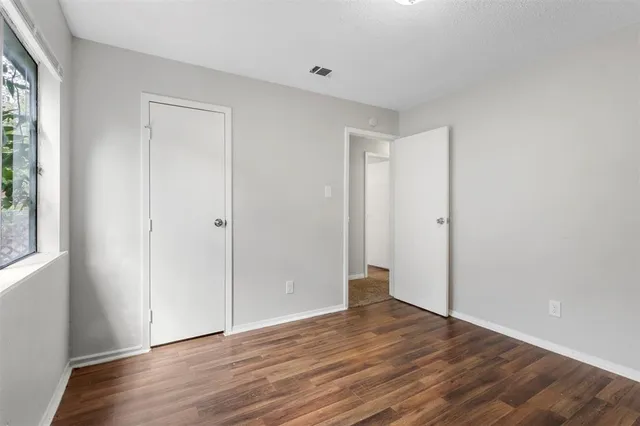 an empty room with wooden floor and a ceiling fan