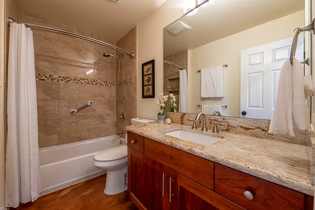 a bathroom with a granite countertop sink toilet and shower