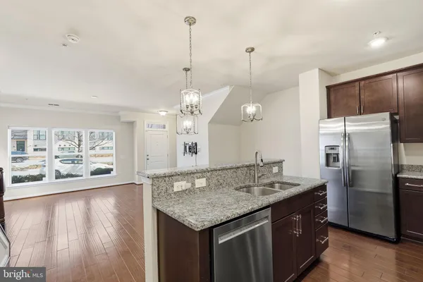 a kitchen with stainless steel appliances granite countertop a sink a refrigerator and a wooden floor