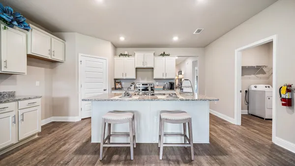 a kitchen with refrigerator a stove a sink and chairs