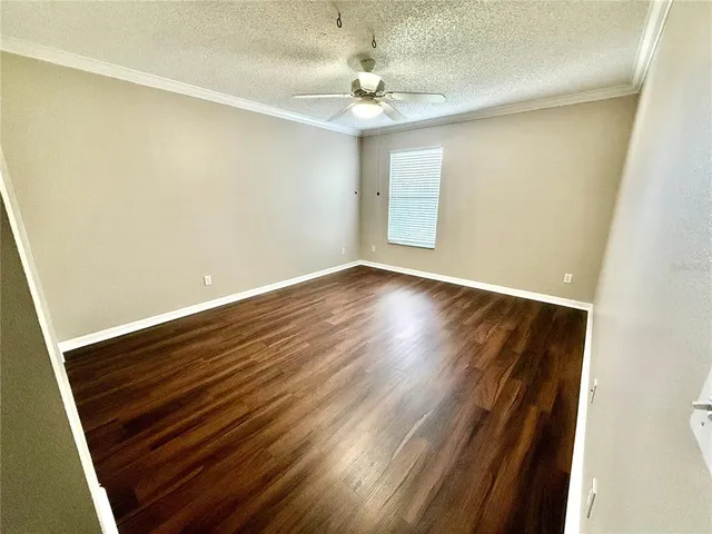 an empty room with wooden floor and fan