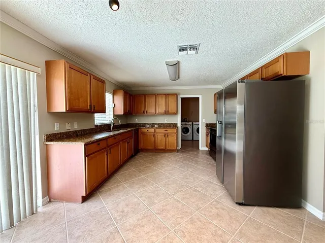 a large kitchen with stainless steel appliances granite countertop a refrigerator and a stove top oven