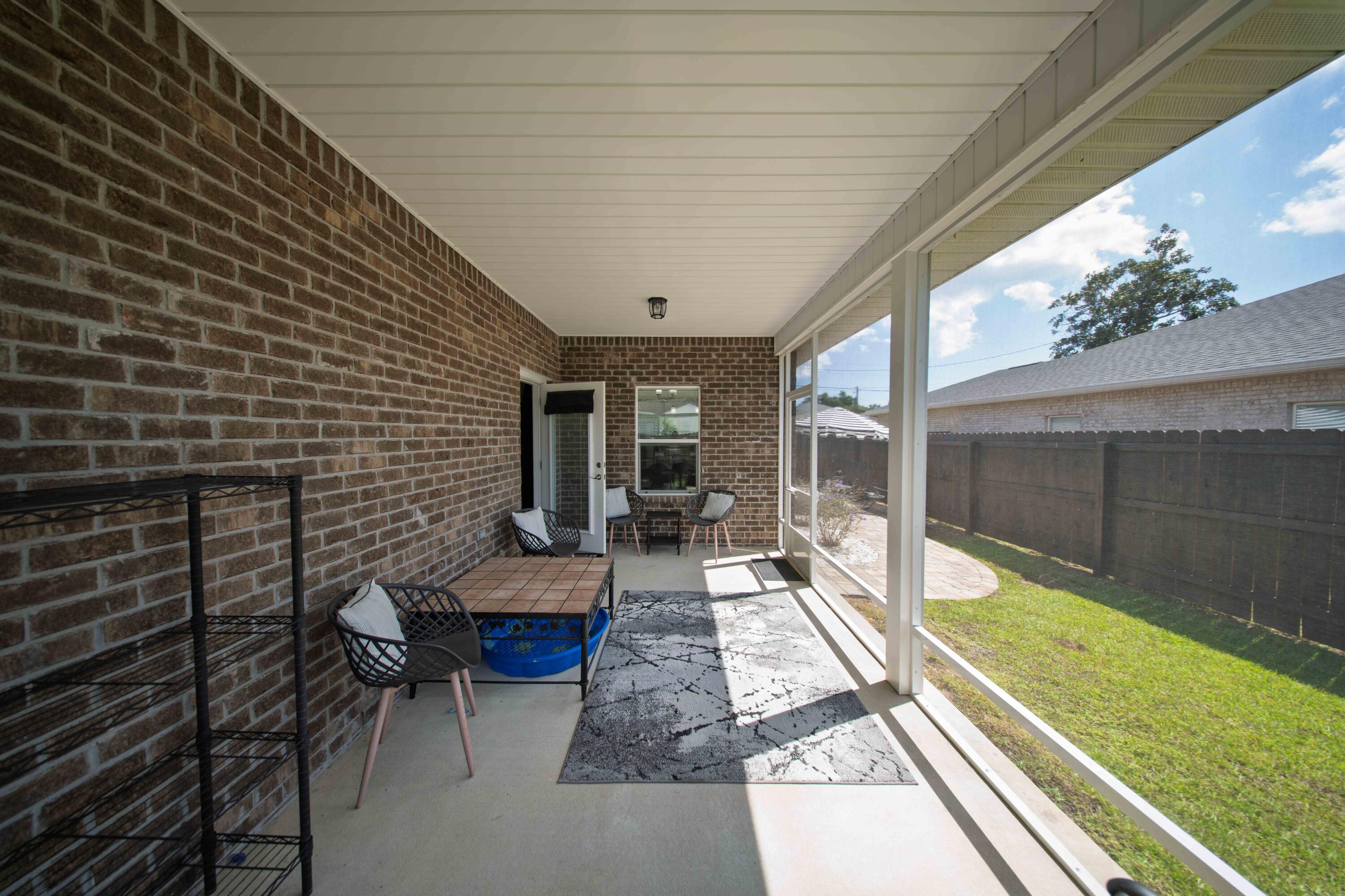 474 Sara Avenue Mary Esther, FL 32569 - Photo 17 of 46 a view of a patio with chairs and floor to ceiling window next to a yard