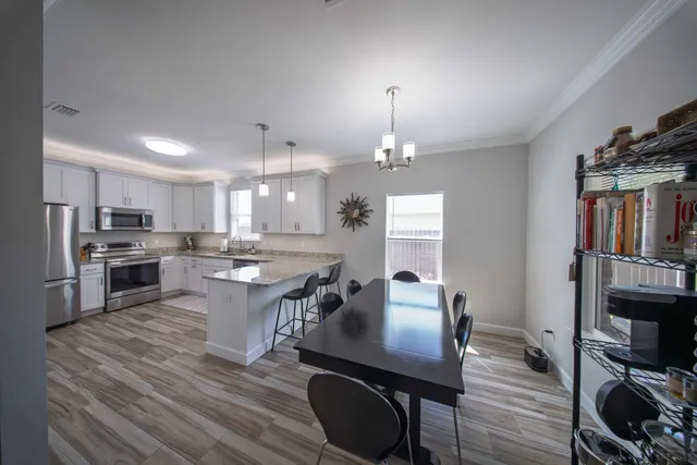 a kitchen with stainless steel appliances a dining table chairs stove microwave and cabinets