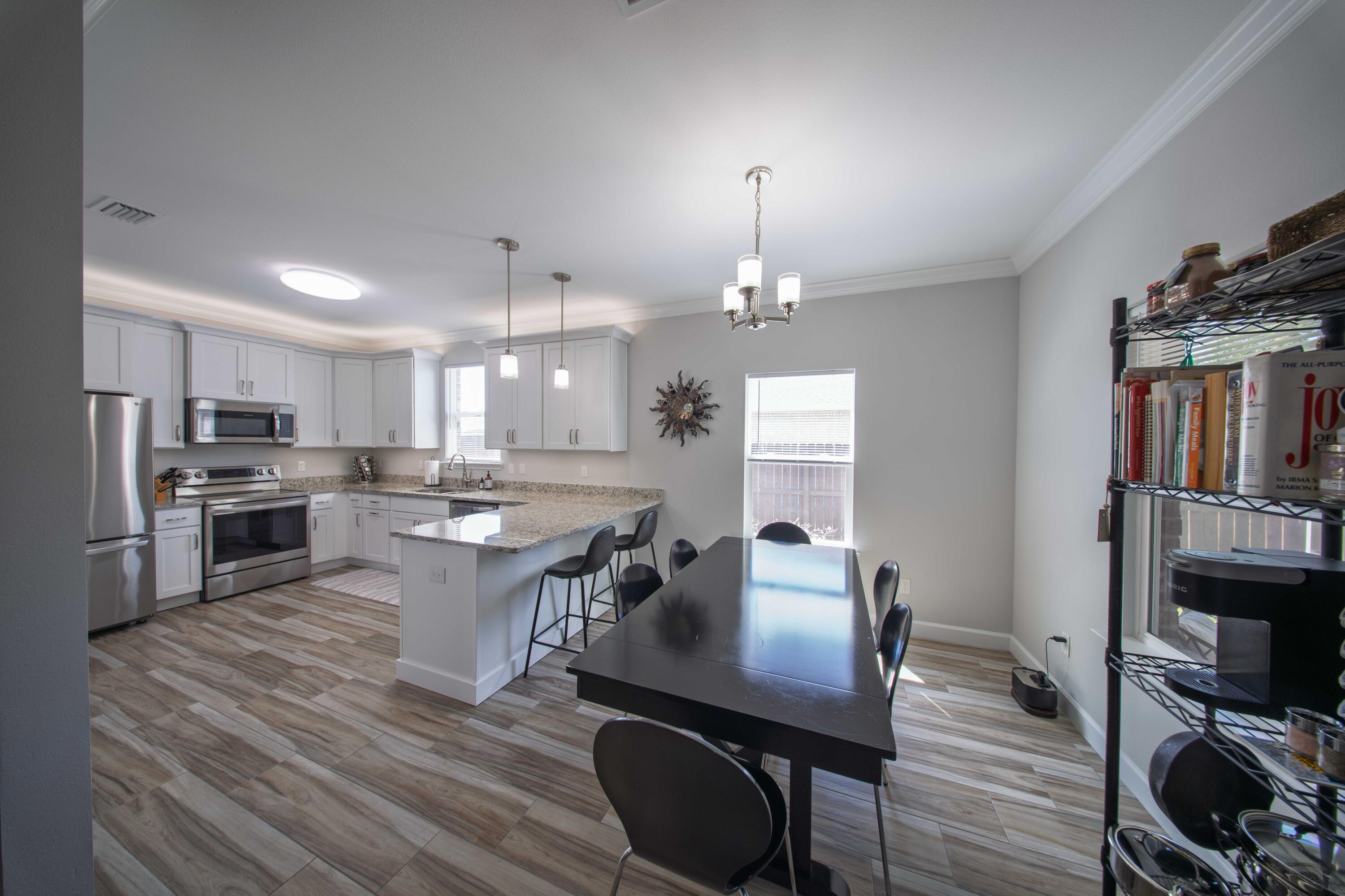 474 Sara Avenue Mary Esther, FL 32569 - Photo 18 of 46 a kitchen with stainless steel appliances a dining table chairs stove microwave and cabinets