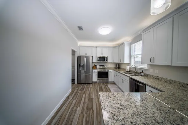 a large kitchen with cabinets wooden floor stainless steel appliances and a window