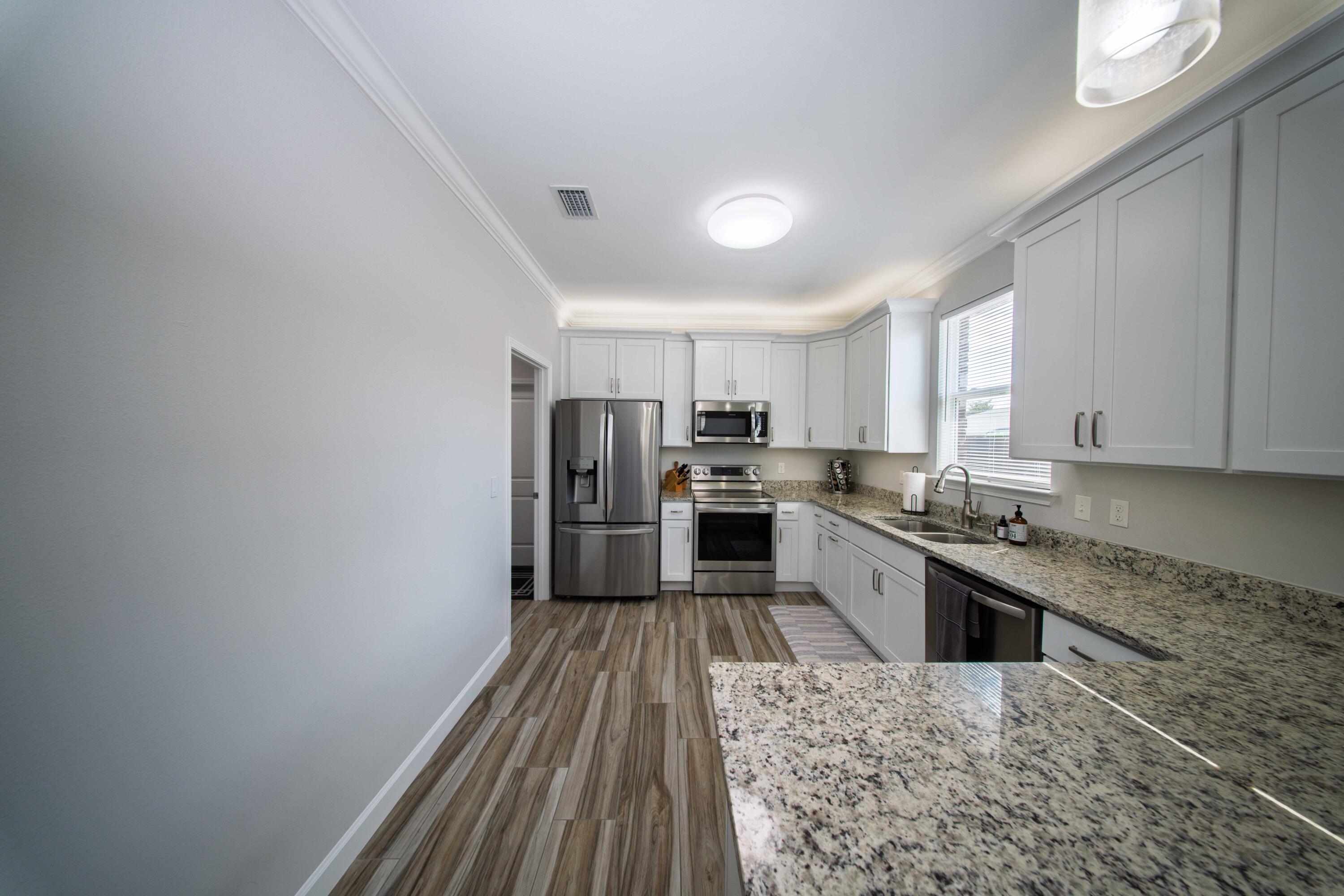 474 Sara Avenue Mary Esther, FL 32569 - Photo 20 of 46 a large kitchen with cabinets wooden floor stainless steel appliances and a window