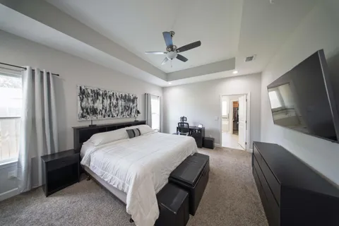 a bedroom with a bed a mirror on desk and a window