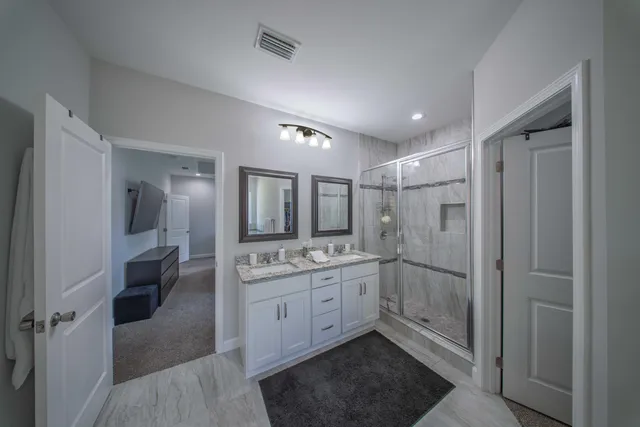 a spacious bathroom with a shower a sink and a mirror