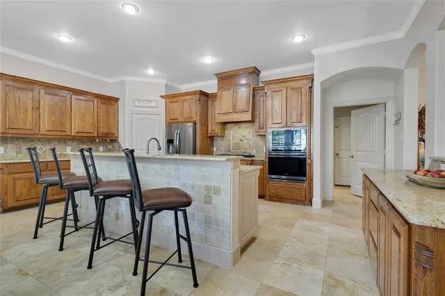 a kitchen with stainless steel appliances granite countertop table chairs and a refrigerator