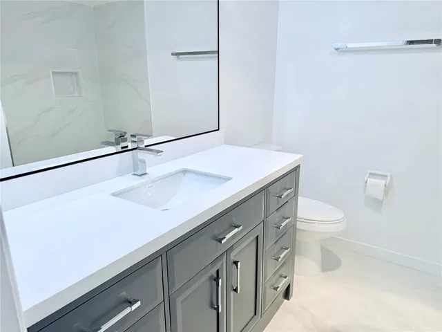 a bathroom with a sink a toilet a mirror and vanity