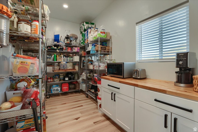 828 South Deer Road Tooele, UT 84074 - Photo 18 of 51 Spacious pantry featuring extensive wire shelving, natural wood-finish countertops, white cabinetry with matte black hardware, wood-finish flooring, and a window with horizontal blinds