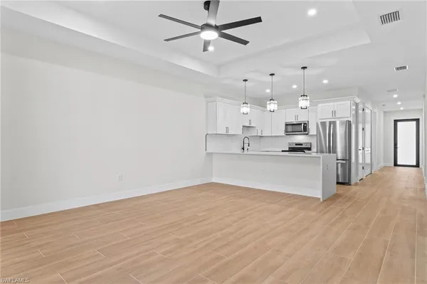 a view of kitchen with kitchen island wooden floor center island and stainless steel appliances