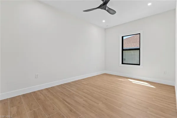 an empty room with a window and ceiling fan
