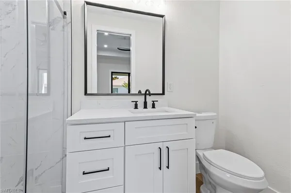 a bathroom with a toilet a sink a vanity and mirror