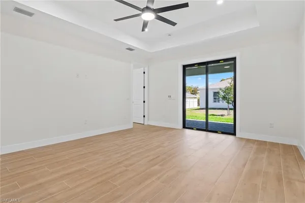 a view of an empty room with window and wooden floor