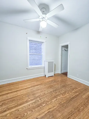 a view of an empty room with window and wooden floor