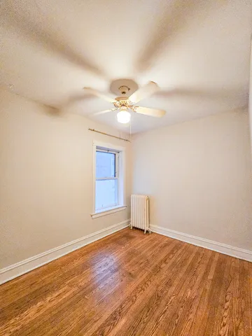 a view of a room with wooden floor and a ceiling fan