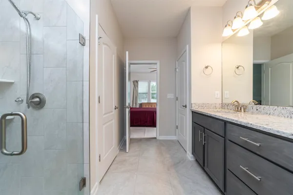 a bathroom with a granite countertop sink two mirror and shower