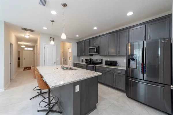 a kitchen with stainless steel appliances granite countertop a refrigerator a sink dishwasher a stove and a refrigerator with wooden floor