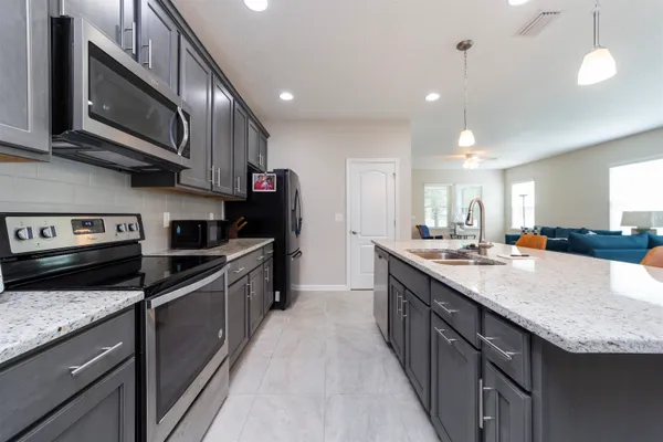 a large kitchen with stainless steel appliances granite countertop a stove a sink and a microwave