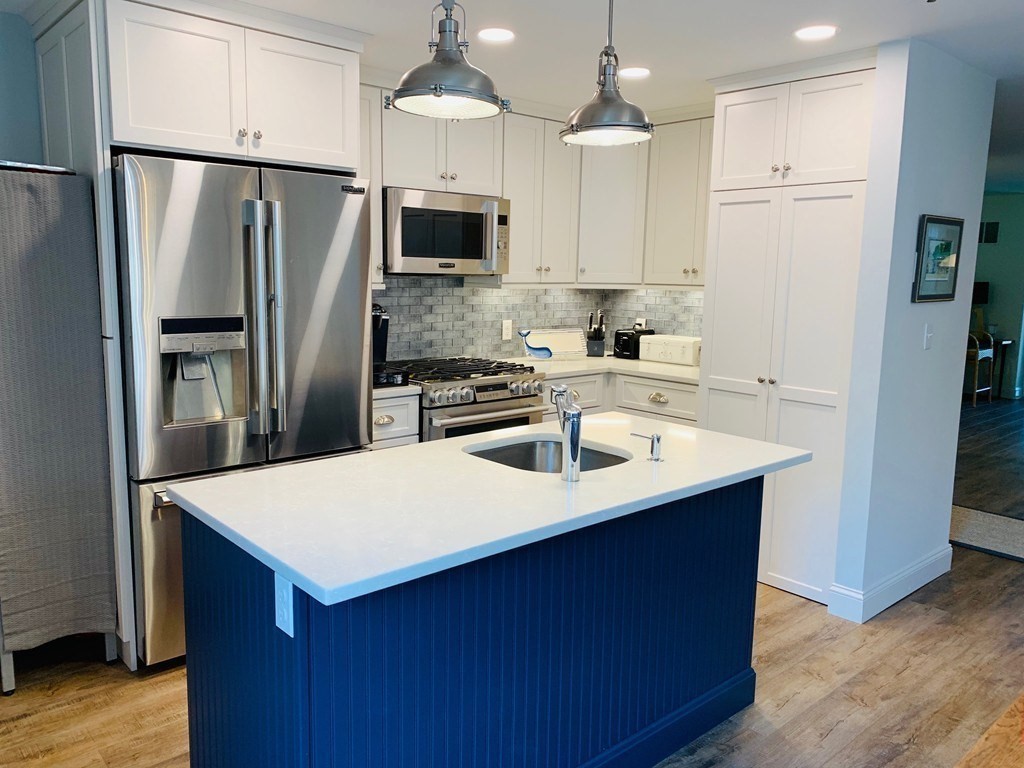 a kitchen with kitchen island a sink stainless steel appliances and refrigerator