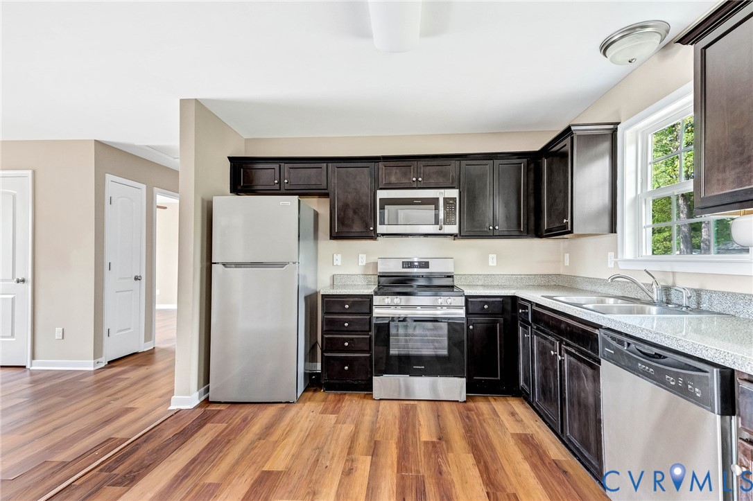 9925 Reymet Court Richmond, VA 23237 - Photo 9 of 30 a kitchen with stainless steel appliances granite countertop a stove top oven a sink dishwasher a refrigerator and a microwave oven with wooden floor