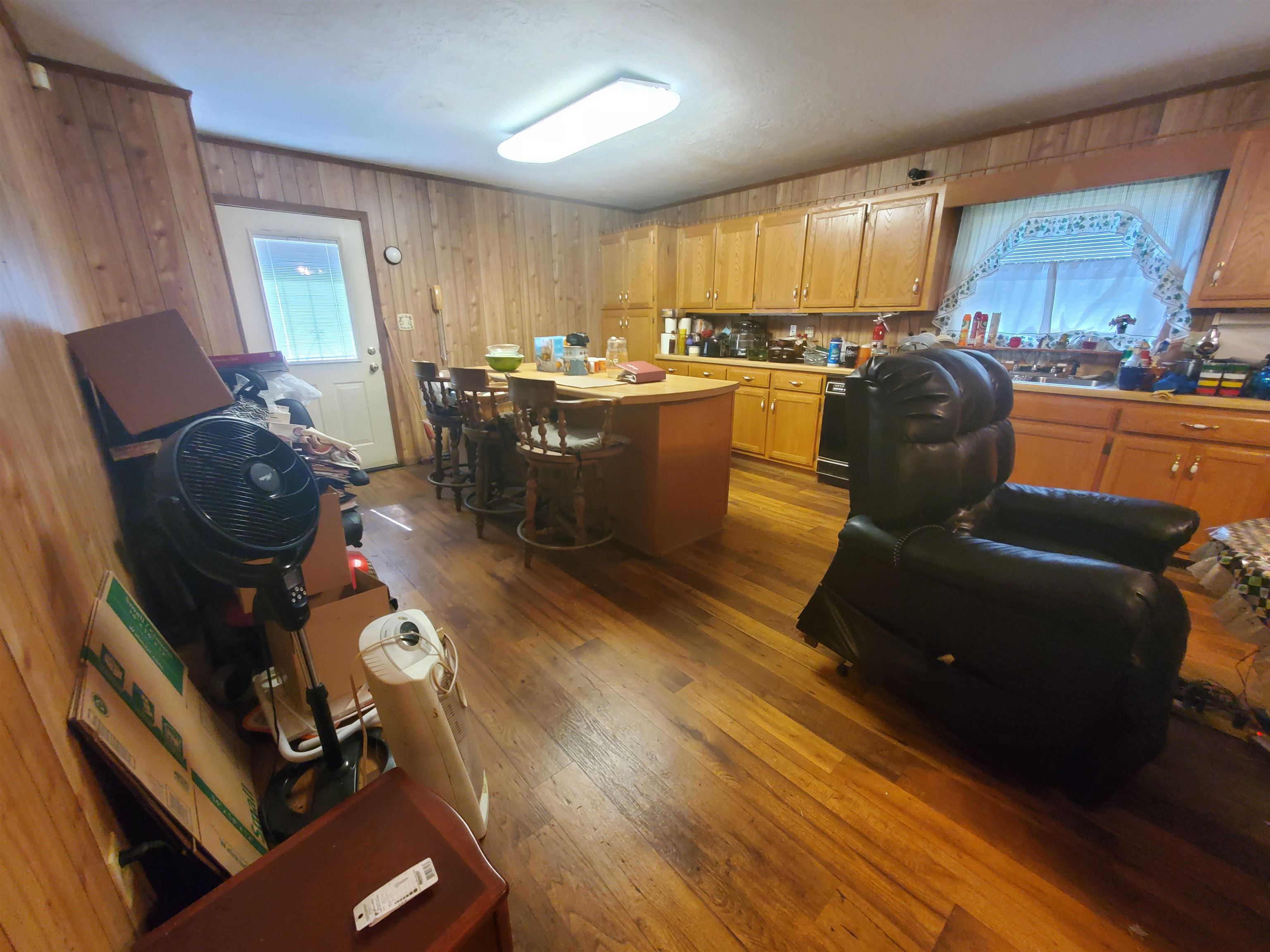 147 Rogers Street Sharon, TN 38255 - Photo 12 of 16 Kitchen with wood-finish flooring, wood paneling, and a central island with bar seating